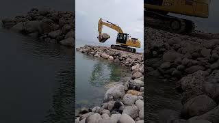 Armour rock piled up on the beach Catterpilar backhoe [upl. by Ness]