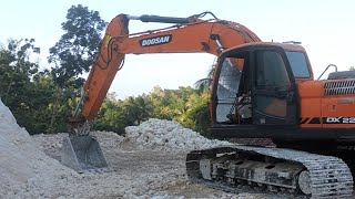 The excavator Doosan DX 225 CA is leveling the rock field and moving it to the dump truck [upl. by Ennovehs]